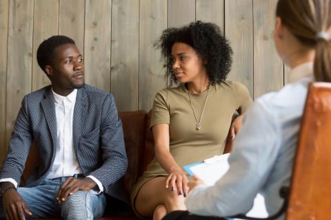 Two parents sit on couch while working with a mediator