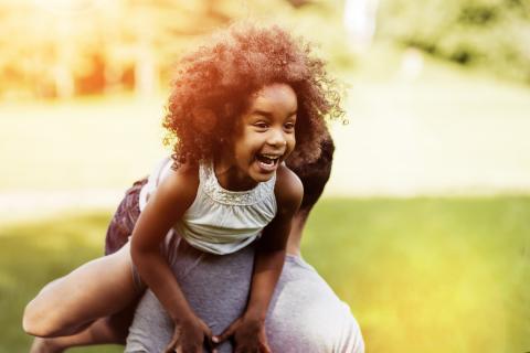 Little girl, laughing, being carried over the shoulder of her father