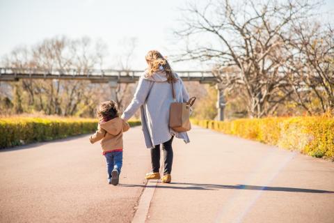 Mother and child walk down a path together at a park.