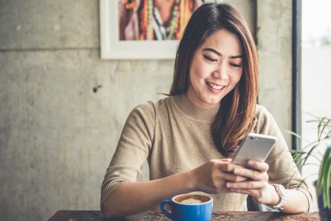 Woman looks at her phone over coffee. 