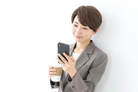 Businesswoman checks her phone for messages while drinking her morning cup of coffee