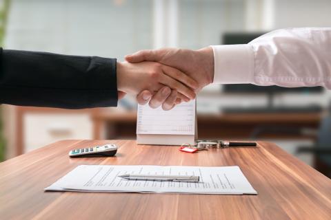 Two adults reach an agreement and shake hands.