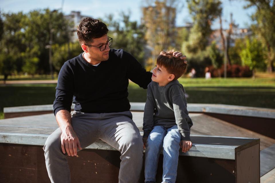 Dad having serious discussion with son on bench.