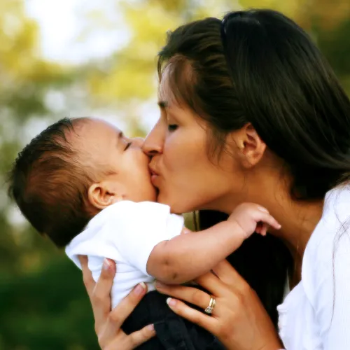 Mother holding and kissing infant