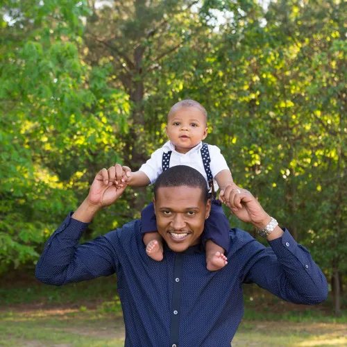 Father carries baby on shoulders outside