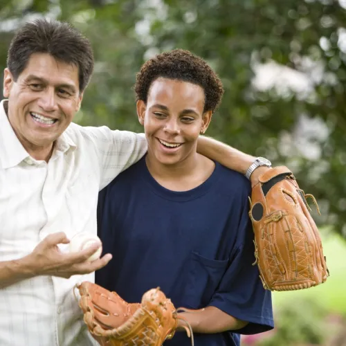 A teenager and his stepfather play catch outside.
