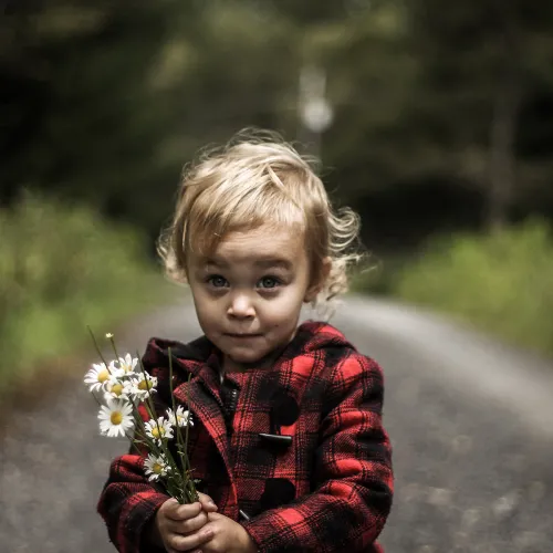 Little girl holding flowers looks playfully at the camera