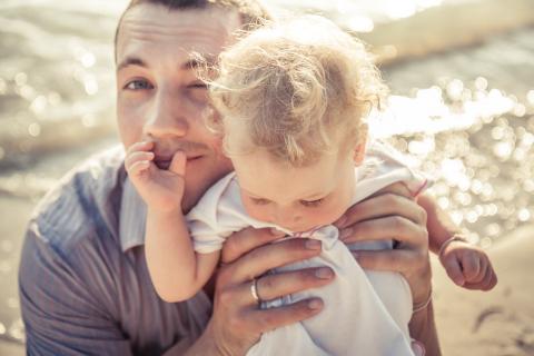 Father holding his young child on the beach