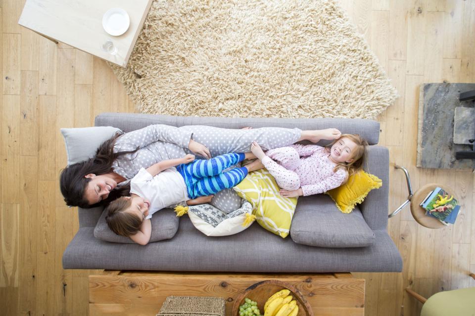 Mother, son, and daughter cuddle on the couch in their pajamas.