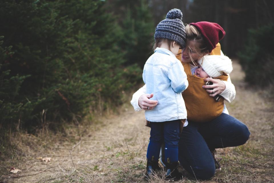 A mom comforts her children as they walk through the park.