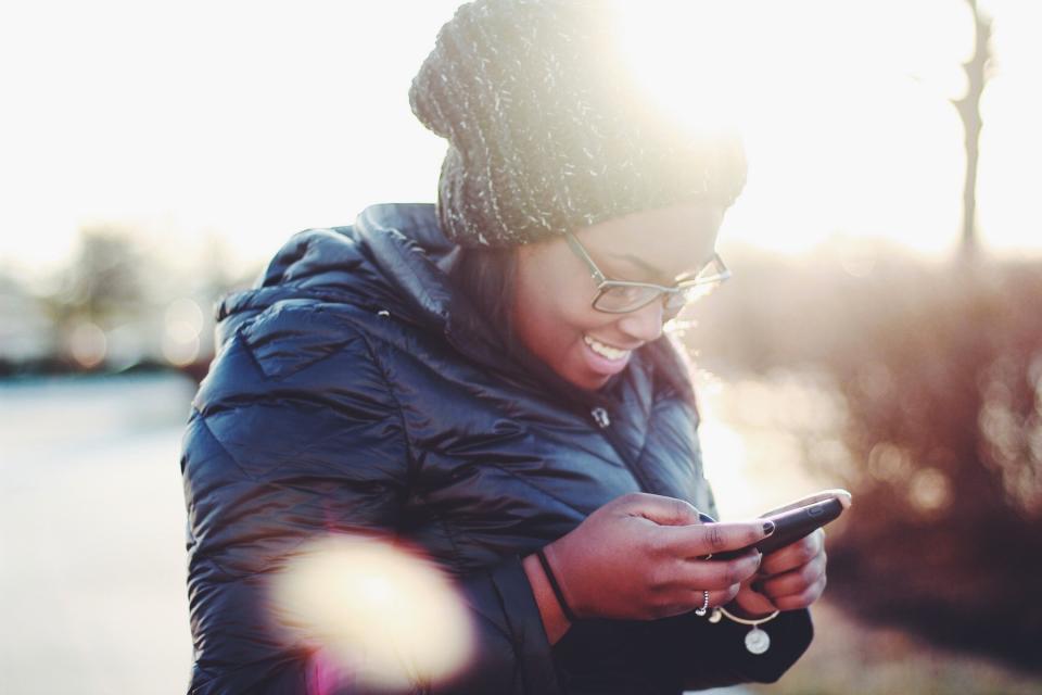 Woman smiles as she looks at her phone.