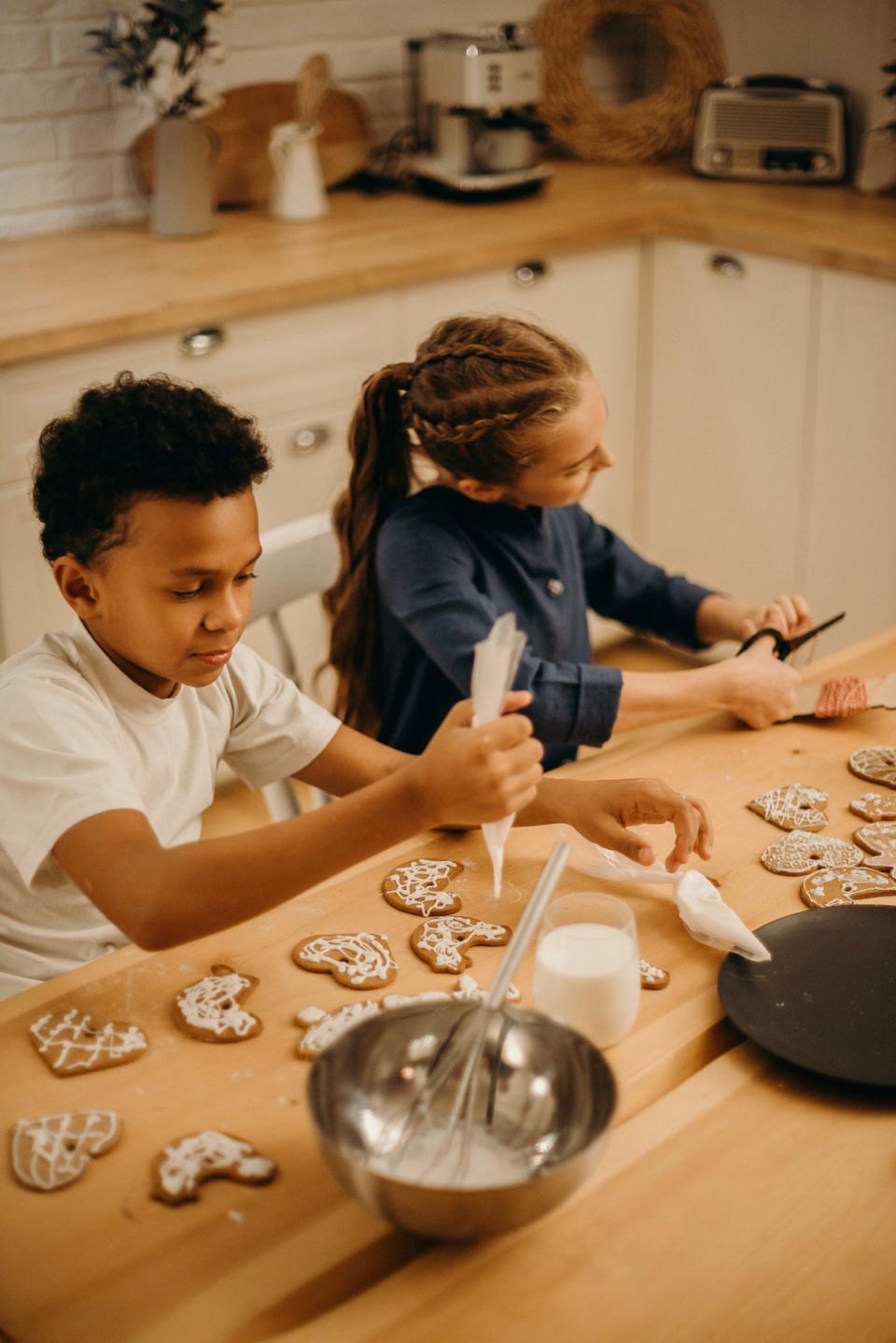 Two kids decorate cookies in the kitchen