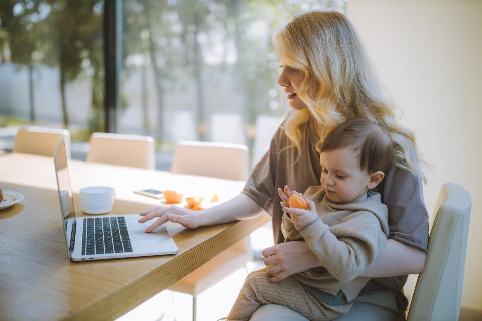 woman with baby in lap with a laptop