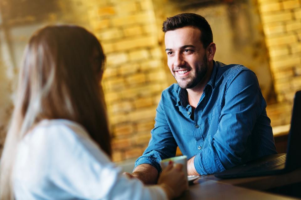 A man and woman sit together at a table and have a conversation.