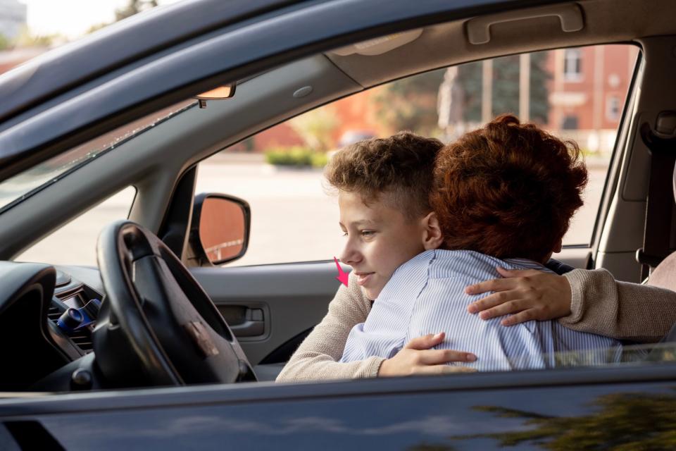 Mom hugging son in car.